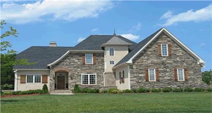 House in the country French architectural style with two stories, stucco and stone exterior and steep rooflines.