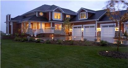 Night view of large Shingle style home plan with white trim and 3-car garage.